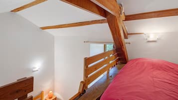 Ein Schlafzimmer mit einem Holzbett, einem Nachttisch mit Lampe und einem Fenster mit Blick auf Bäume.