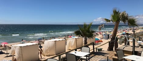 Eine Terrassenförmige Sitzgelegenheit am Strand mit Tischen und Stühlen mit Blick auf das Meer.