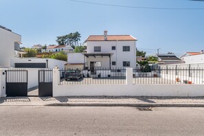Ett bostadsområde med ett vitt tvåvåningshus, ett garage och en asfalterad uppfart.