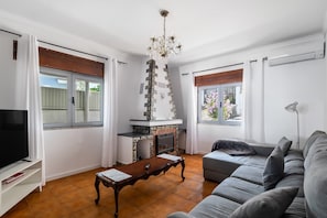 Ein Wohnzimmer mit Kamin, einer Couch, einem Fernseher und einer Deckenleuchte.