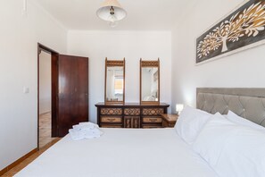 A bedroom with a bed, a dresser, a mirror, and a wall art piece. - Holiday Home 'Vivenda Alves' with Mountain View, Wi-Fi and Air Conditioning (Charneca da Caparica)