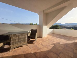 Eine Terrasse mit Tisch und Stühlen, Blick auf die Landschaft und ein klarer Himmel.