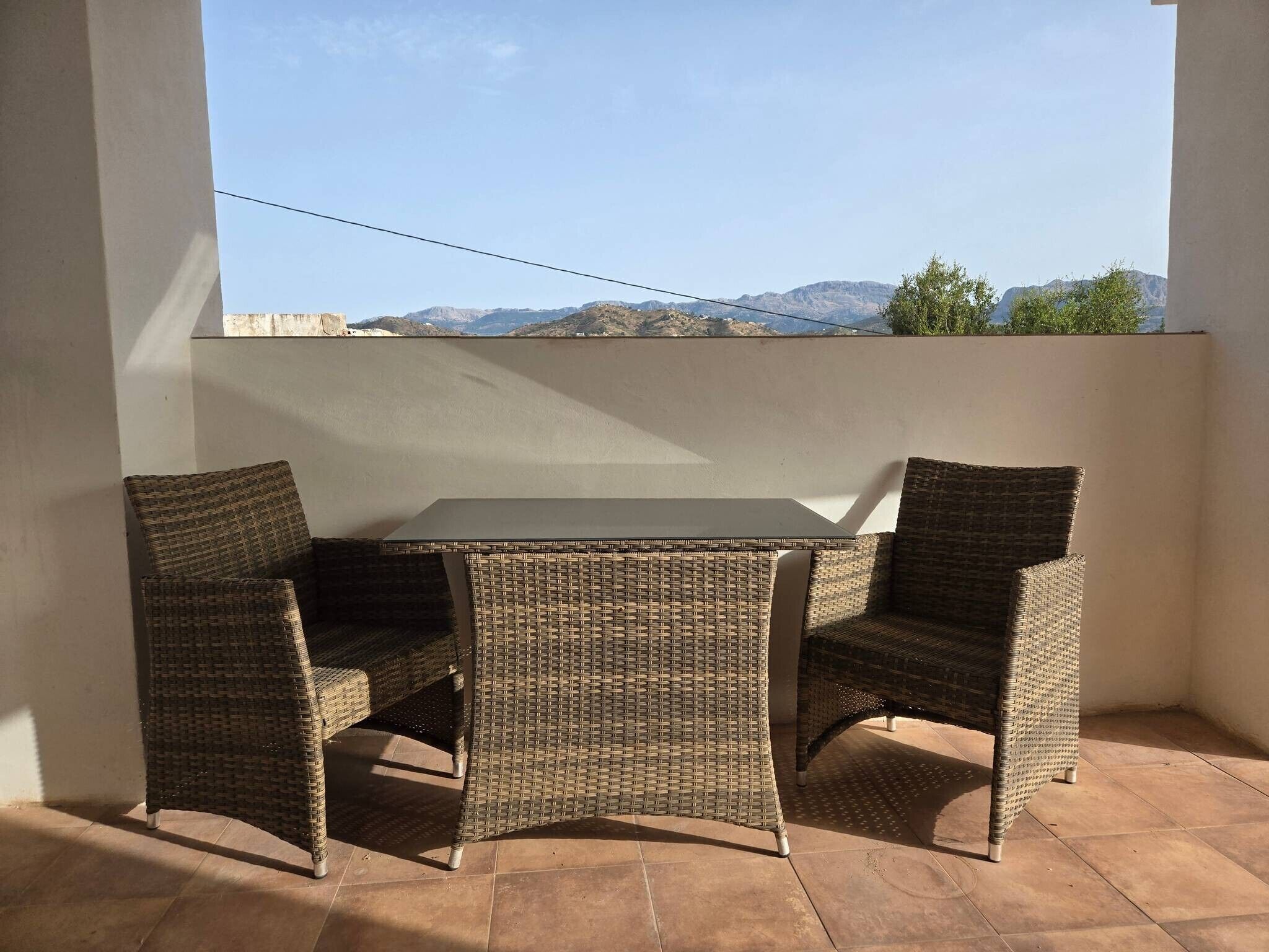 A balcony with wicker furniture and a view of mountains.
