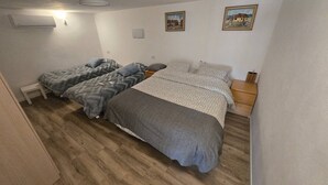Una habitación con dos camas, piso de madera y dos cuadros en la pared.