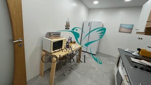 Eine kompakte Küche mit Mikrowelle, kleinem Kühlschrank und einem Holztisch mit Toaster.