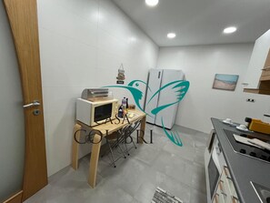 Eine kompakte Küche mit Mikrowelle, kleinem Kühlschrank und einem Holztisch mit Toaster.