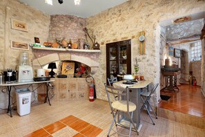 Una cocina rústica con chimenea, una mesa de comedor con sillas y varios electrodomésticos.