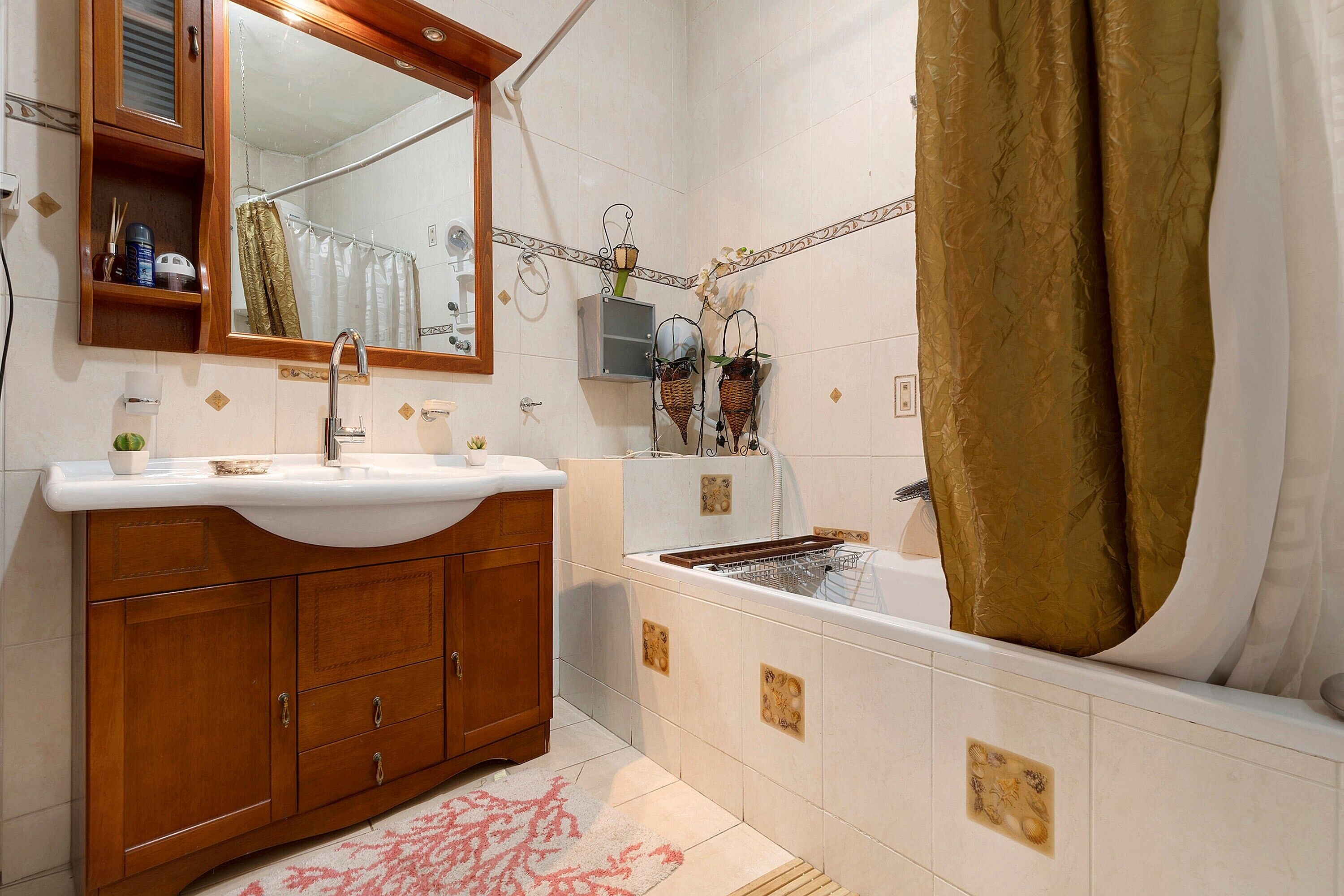 A bathroom with a wooden vanity, a white sink, a bathtub, and a shower area.