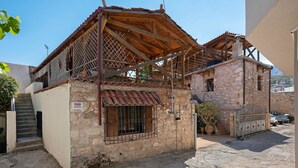 Un edificio de piedra de dos pisos con techo de tejas, una reja metálica y una escalera que conduce a la entrada.