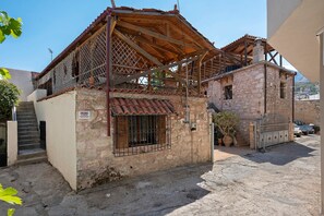 Un edificio de piedra de dos pisos con techo de tejas, una reja metálica y una escalera que conduce a la entrada.