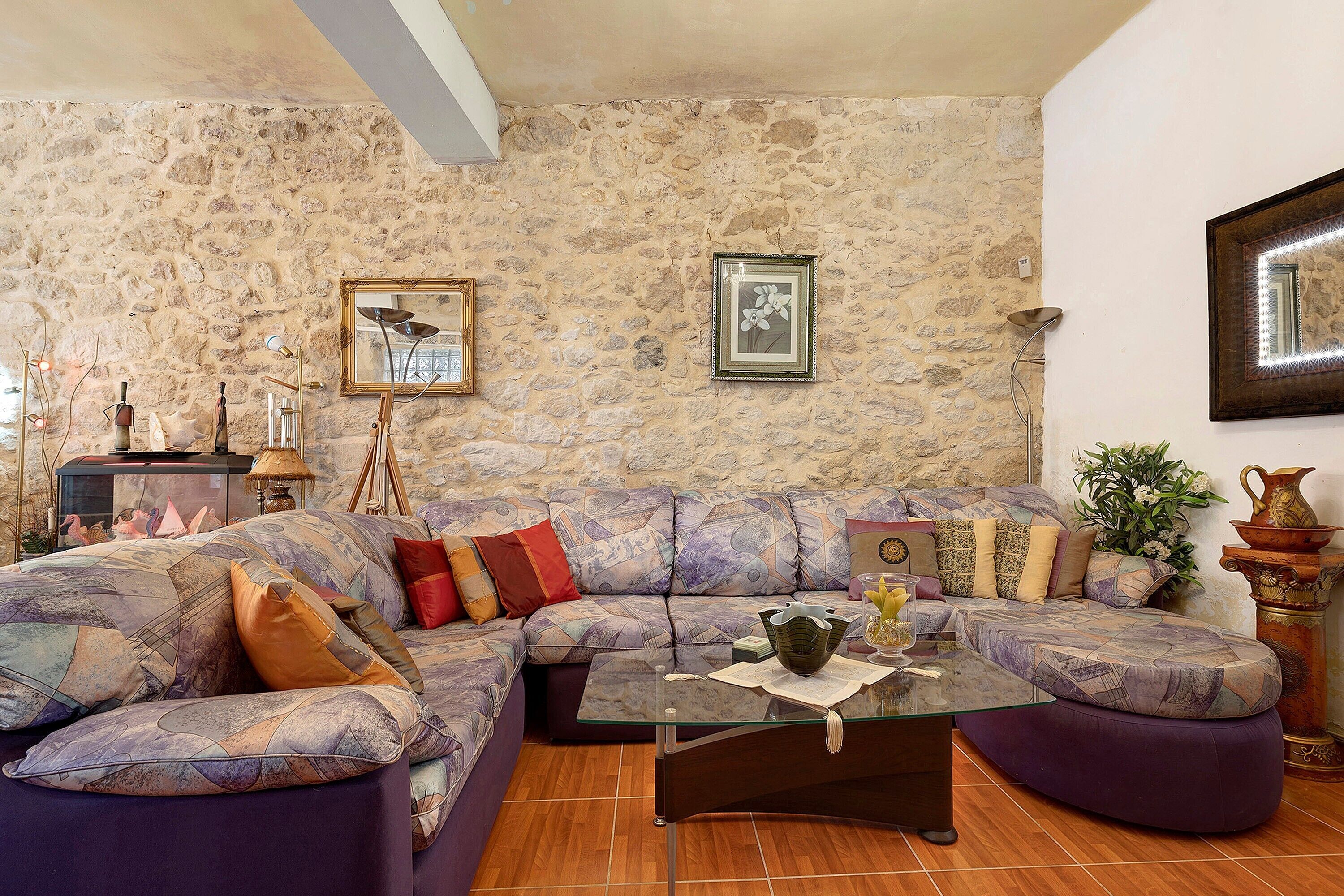 A living room with a stone wall, a sofa set, a coffee table, and decorative items.