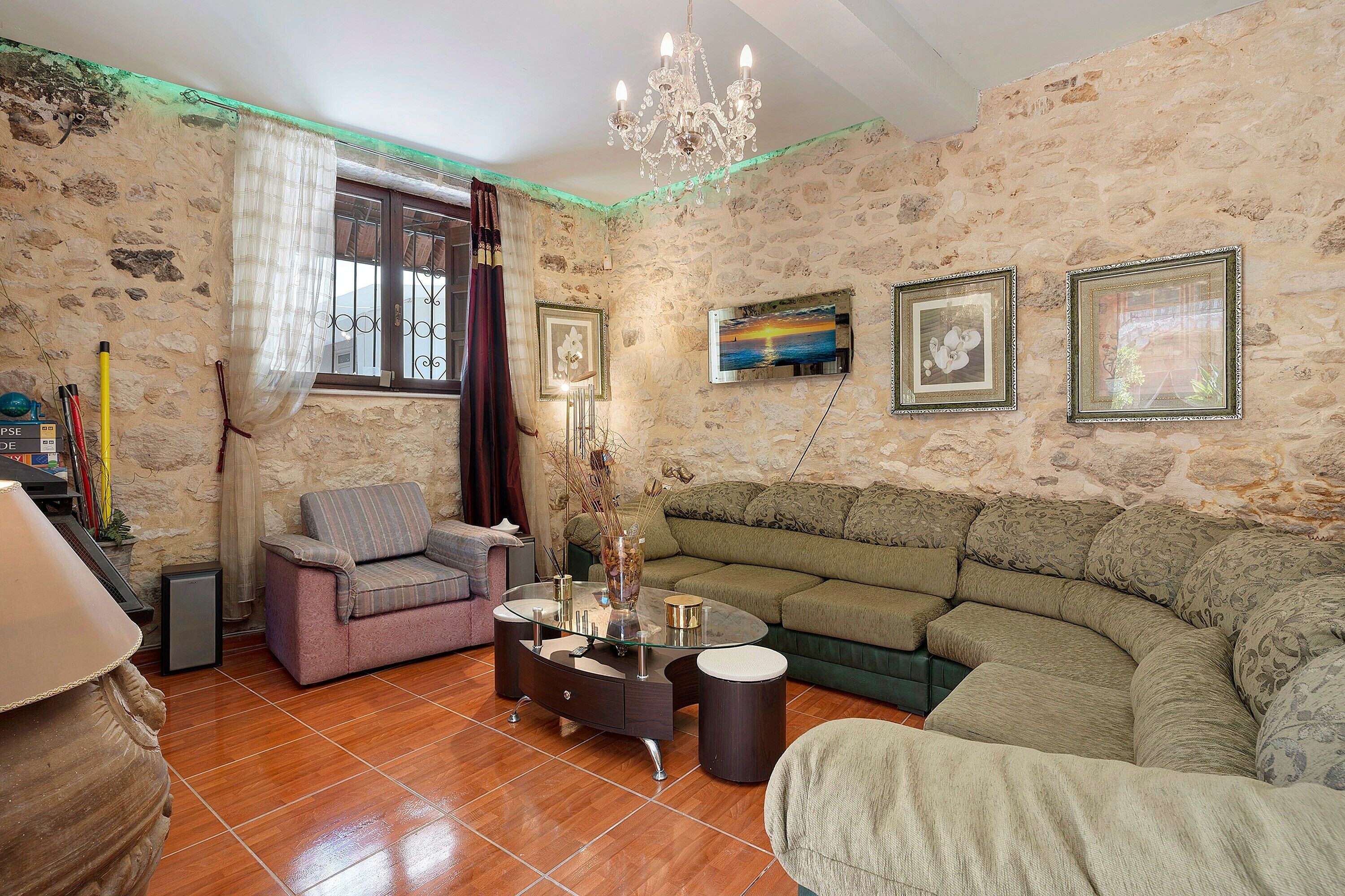 A living room with a sofa, armchairs, a coffee table, and a chandelier.
