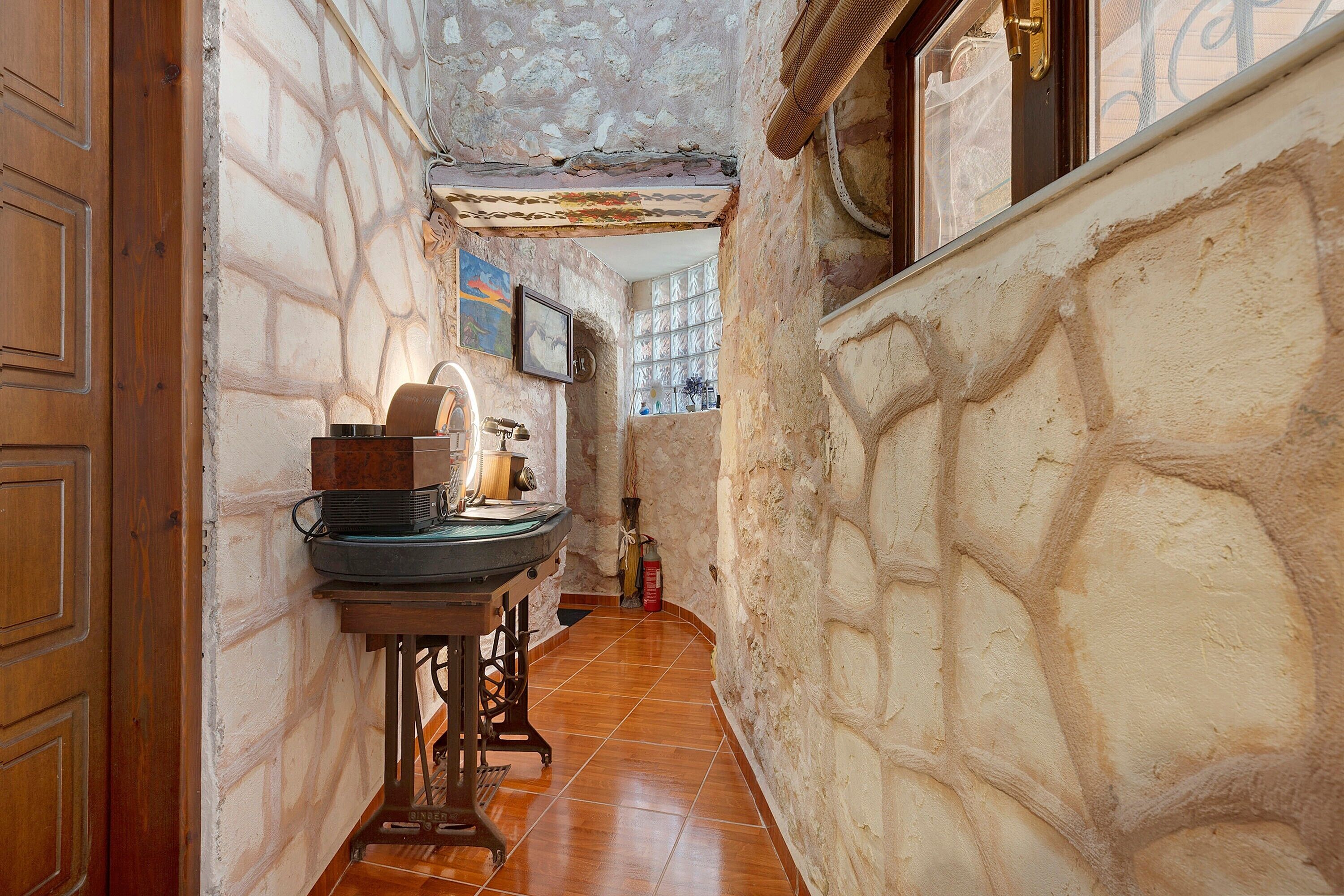 Un pasillo estrecho con paredes de piedra, una puerta de madera, un lavabo y una ventana con vistas.