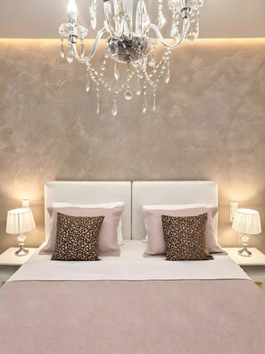 Ein Schlafzimmer mit einer Chandelierleuchtre, zwei Nachttischen, zwei Lampen und zwei Kissen mit Leopardenmuster.