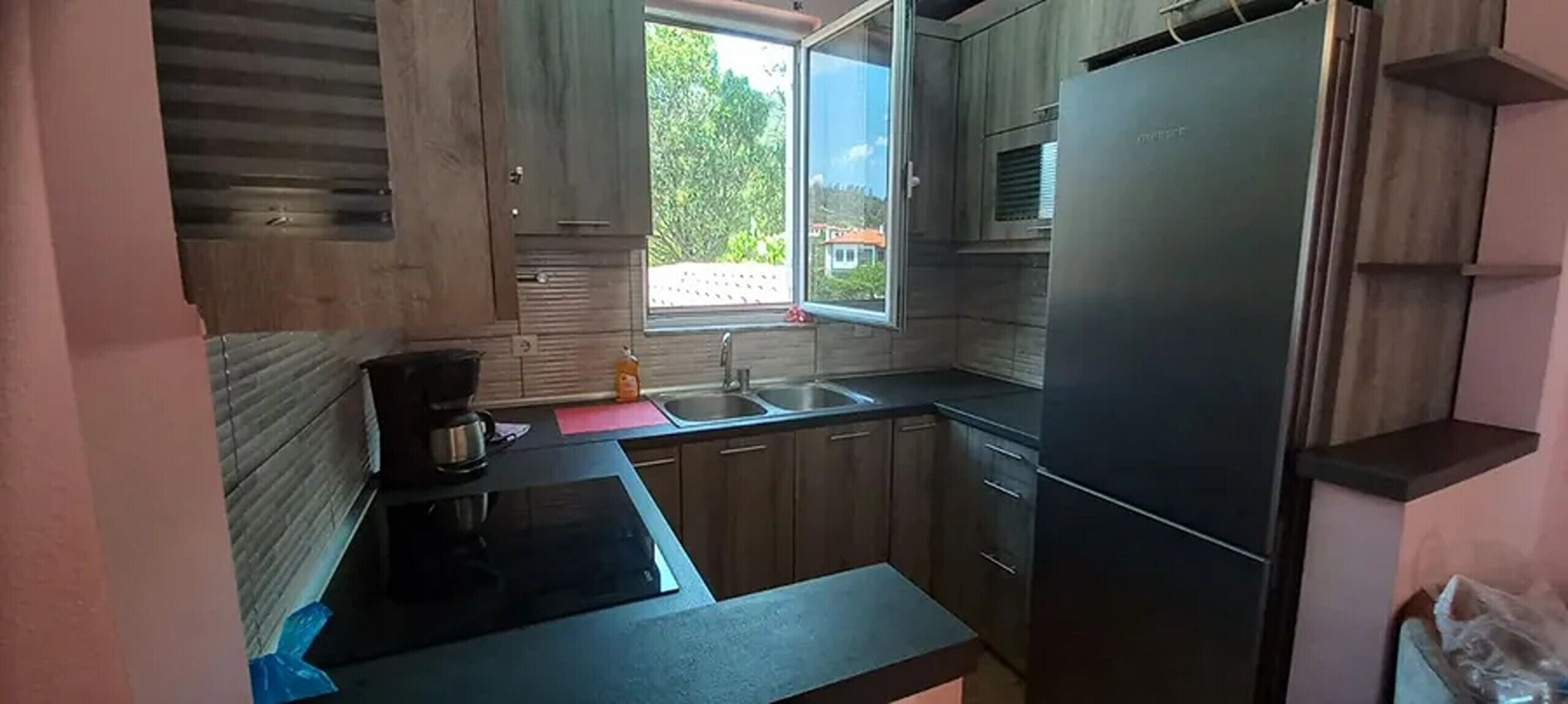 Une cuisine de taille réduite, équipée d’une cuisinière intégrée, d’un évier et d’un réfrigérateur.