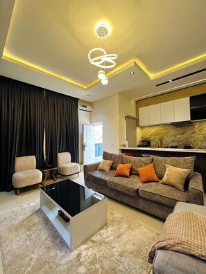 A modern living room with a sofa, coffee table, and a kitchen area in the background.