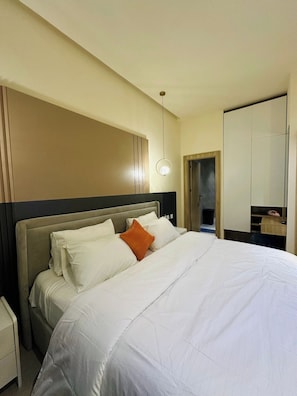 Una habitación de hotel con una cama grande, una mesita de noche, un armario y un espejo.