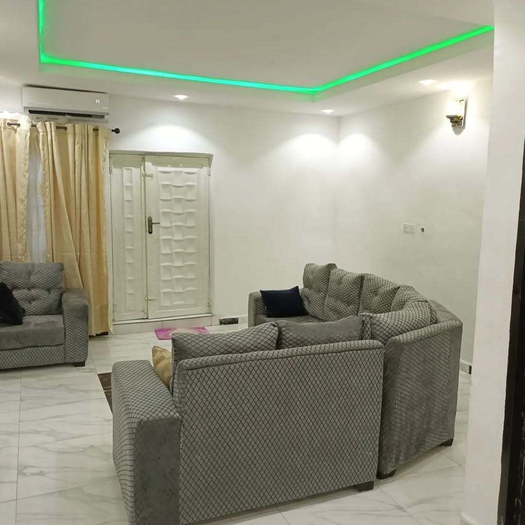 A living room with a sectional sofa, a smaller sofa, and a coffee table. There is a door with a glass panel and a curtain.