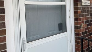 En vit ytterdörr med en glaspanel och ett handtag i metall.