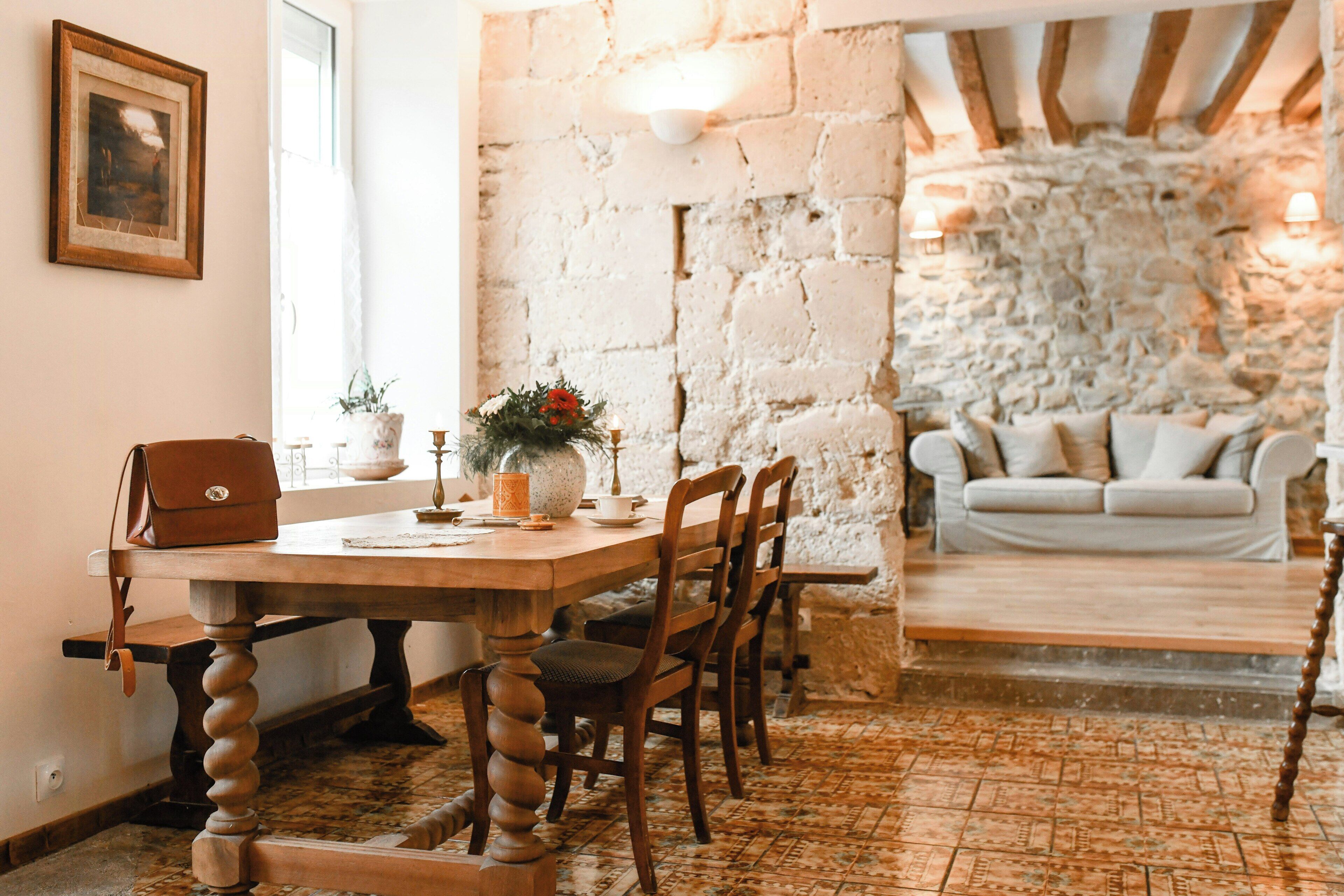 Un coin repas rustique avec une table en bois, des chaises et un mur en pierre.