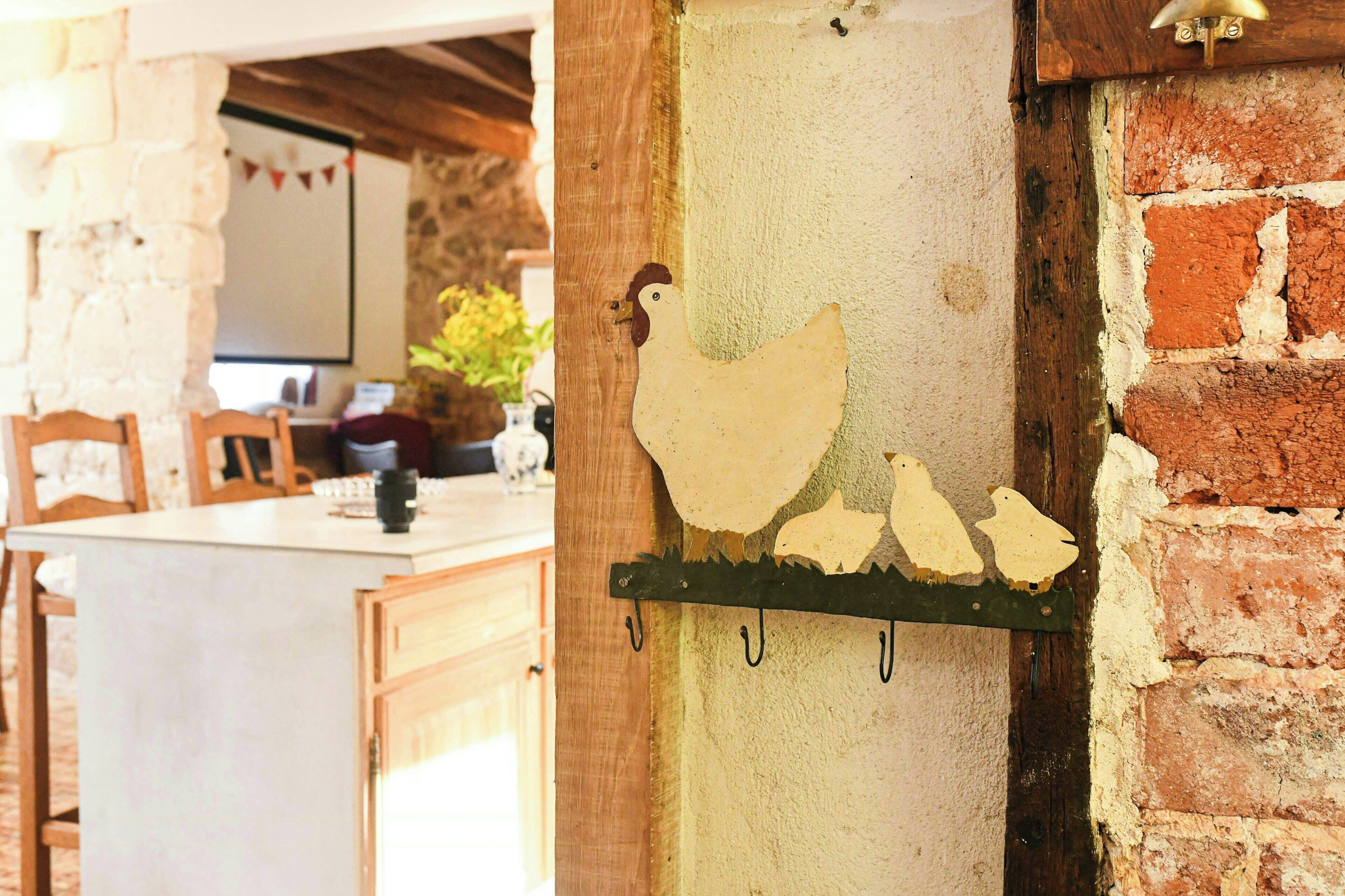 Una cocina rústica con paredes de ladrillo visto, una mesa de madera y un adorno de gallo colgado en la pared.