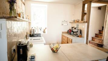 A kitchen with a central island, a stove, and a coffee machine.
