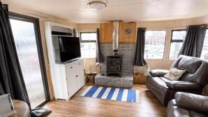 A compact living space with a television, a fireplace, a sofa, and a striped rug. - Riverside Escape - Newark on Trent (Newark)