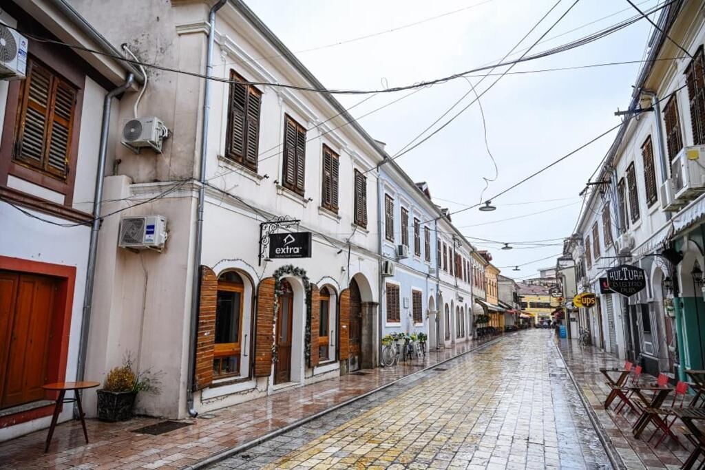 Una calle estrecha flanqueada por edificios, algunos con letreros de comercios.