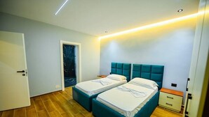A room with two beds, a door, and a nightstand. - Mon Ami Boutique Hotel  (Shkoder)