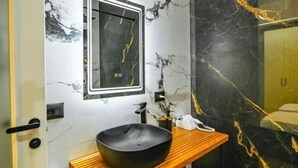 A bathroom with a black marble wall, a wooden vanity, and a black basin. - Mon Ami Boutique Hotel  (Shkoder)