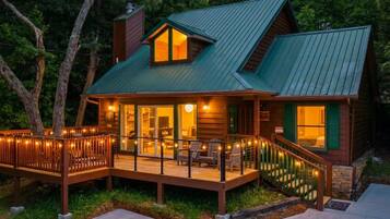 A cabin with a deck, a staircase, and a porch area.