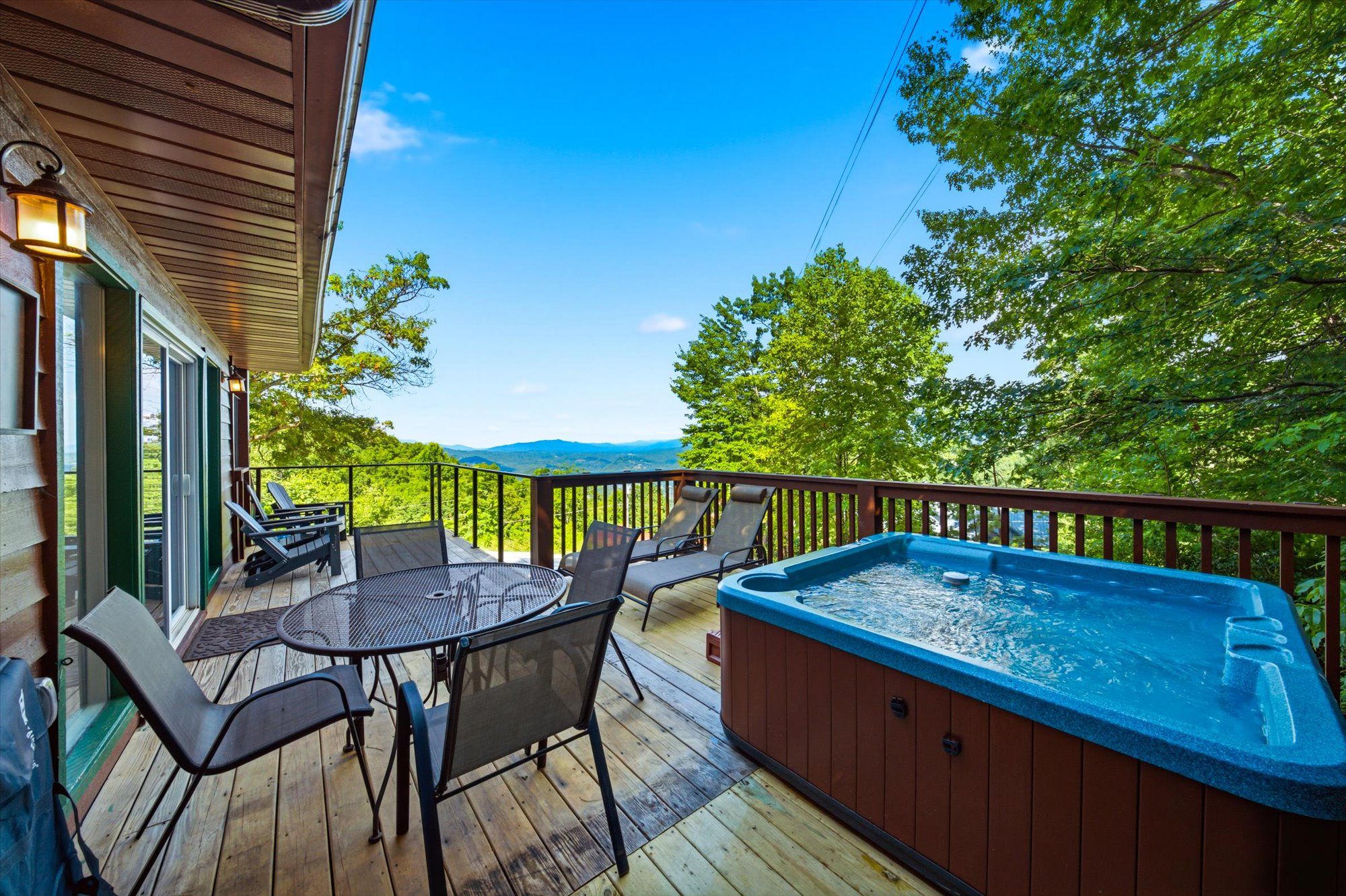 A deck with a hot tub, outdoor seating, and a view of the landscape.