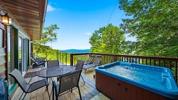 A deck with a hot tub, outdoor seating, and a view of the landscape.
