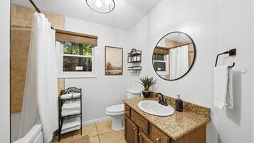 A bathroom with a bathtub, toilet, sink, and a mirror.