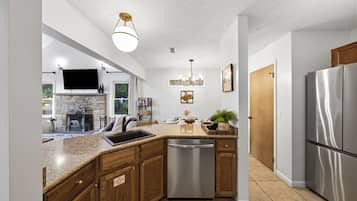 A modern kitchen with granite countertops, stainless steel appliances, and wooden cabinetry.