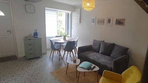 Un espai habitable compacte amb zona de menjador, un sofà i una taula petita amb els mandins a sobre.