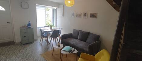 Un espacio habitable compacto con comedor, sofá y una mesita con mandos a distancia.