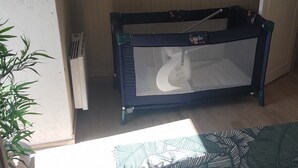 Una habitació amb un parc infantil, una catifa amb dibuixos i un panell floral al mur.