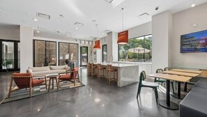 Ein modernes Interieur mit einer Couch, Sesseln, einem Essbereich und einer Küchenzeile.