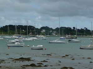 A marina with various boats docked, surrounded by a calm sea and a backdrop of houses and trees. - Apartment in a beautiful house in the countryside near the ocean. (Plévenon)