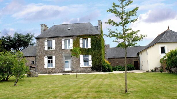 A stone building with multiple windows and a lawn in front. - Apartment in a beautiful house in the countryside near the ocean. (Plévenon)