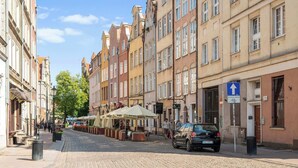 Mukulakivikatu, jonka varrella on historiallisia rakennuksia, ulkona olevia istumapaikkoja ja pysäköity auto.