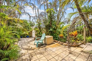 Eine Terrassenanlage mit Fliesenboden, einem grünen Stuhl und verschiedenen tropischen Pflanzen.