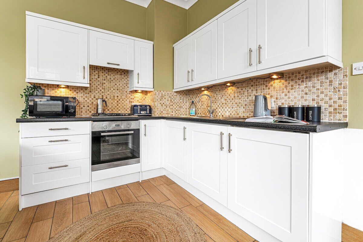 A kitchen with white cabinets, a microwave, a toaster, and a coffee maker.