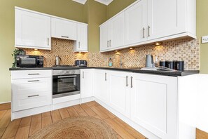 A kitchen with white cabinets, a microwave, a toaster, and a coffee maker. - Edinburgh CITY Centre 2BR Apartment (Edinburgh)