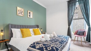 A bedroom with a bed, pillows, a blanket, a chair, and a nightstand. - Edinburgh CITY Centre 2BR Apartment (Edinburgh)