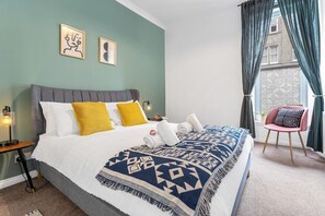A bedroom with a bed, pillows, a blanket, a chair, and a nightstand. - Edinburgh CITY Centre 2BR Apartment (Edinburgh)