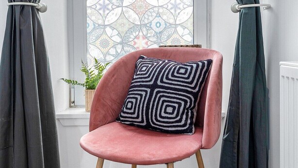 A chair with a geometric pillow in front of a window with a patterned view. - Edinburgh CITY Centre 2BR Apartment (Edinburgh)