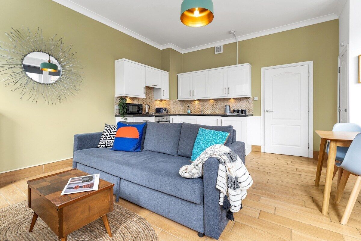 A living room with a sofa, coffee table, and a kitchen in the background.