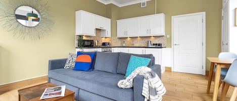 A living room with a sofa, coffee table, and a kitchen in the background.